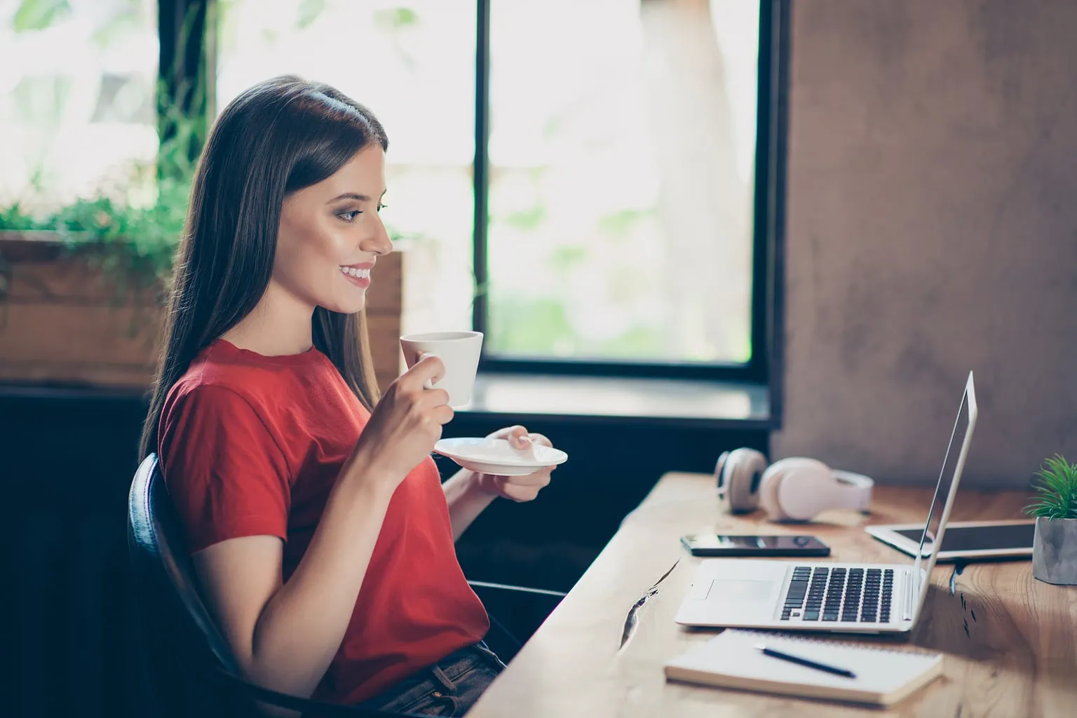 Die besten Nebenverdienst-Möglichkeiten im digitalen Zeitalter Eine Frau sitzt vor einem Laptop und hält eine Tasse Kaffee in der Hand